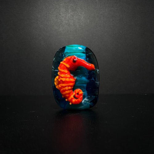 Red and Orange Sea Horse Bead on an Ocean Themed Back Ground.